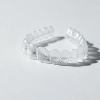 Close-up of clear Invisalign aligners on a white background, highlighting their discreet appearance, clean image, no text